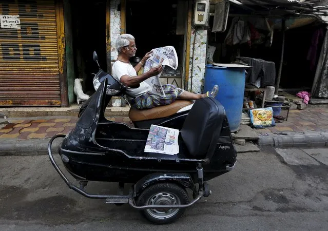 A man reads a newspaper as he sits on his scooter outside a shop in the western Indian city of Ahmedabad April 8, 2015. (Photo by Amit Dave/Reuters)