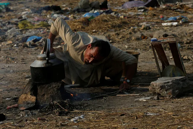 A man blows air to start a fire as he brews tea on a littered ground in Karachi, Pakistan January 18, 2017. (Photo by Akhtar Soomro/Reuters)