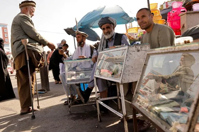 Afghan men sit behind their currency exchange stalls in Kabul, Afghanistan on October 7, 2021. (Photo by Jorge Silva/Reuters)