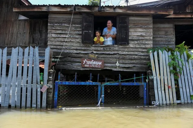 A mother and daughter are seen on the second floor of their house in a flooded area in Ban Sai village, Ban Mi district in Lopburi province, Thailand, September 30, 2021. (Photo by Panumas Sanguanwong/Reuters)