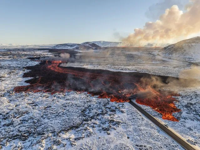 A view of lava crossing the main road to Grindavík and flowing on the road leading to the Blue Lagoon, in Grindavík, Iceland, Thursday, February 8, 2024. (Photo by Marco Di Marco/AP Photo)