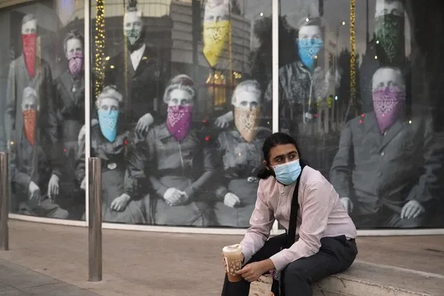 In this Wednesday, December 9, 2020, file photo, a man takes a coffee break in front of a COVID 19-themed mural, in Beverly Hills, Calif. On Monday, Oct. 11, 2021, California's coronavirus death toll reached 70,000. (Photo by Marcio Jose Sanchez/AP Photo/File)