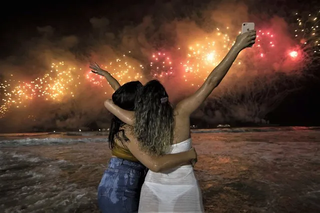 People bring in the New Year as they watch fireworks explode over Copacabana Beach in Rio de Janeiro, Brazil, early Sunday, January 1, 2023. (Photo by Bruna Prado/AP Photo)