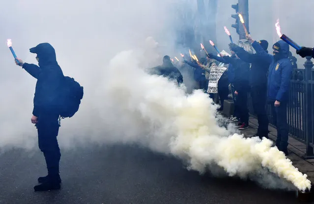 Supporters of various Ukrainian nationalist parties light smoke bombs as they chant slogans during a rally in front of Ukrainian Parliament, in central Kiev, on February 22, 2017. Members and supporters of ultra-nationalists “Svoboda”, “Pravy Sektor” and “National Corpus” political parties gathered on February 22, 2017 to mark the third anniversary of pro-EU protests that toppled pro-Kremlin president Viktor Yanukovych that was followed by Moscow's annexation of the Crimea peninsula and the Russian-backed insurgency in eastern Ukraine. (Photo by Genya Savilov/AFP Photo)