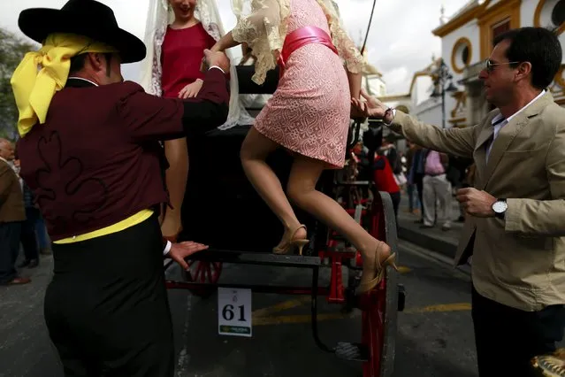 A woman is helped by men to get on a carriage before participating in a carriages exhibition in The Maestranza bullring of the Andalusian capital of Seville, southern Spain April 10, 2016. (Photo by Marcelo del Pozo/Reuters)