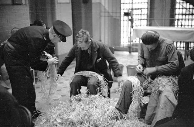 A prison officer supervising prisoners who are untying knots in Post Office string at Strangeways Prison in Manchester, England, 20th November 1948. (Photo by Bert Hardy/Picture Post/Getty Images)