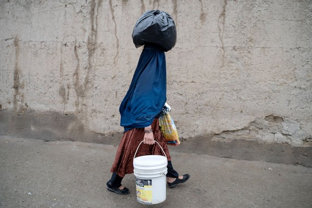 An Afghan burqa-clad woman carrying a plastic bag over her head walks along a street in Kabul on March 27, 2024. (Photo by Wakil Kohsar/AFP Photo)