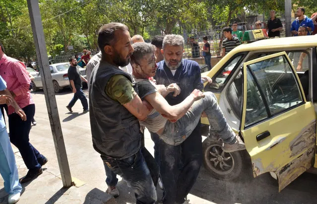 Syrian men carry an injured youth in the government-controlled side of the northern city of Aleppo following fighting between regime forces and rebels on April 28, 2016. The Syrian army was preparing an offensive to retake the whole of Aleppo, as fighting in the divided second city killed 38 civilians in a new blow for a tattered truce. (Photo by George Ourfalian/AFP Photo)