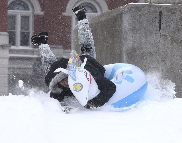 University of Missouri freshman Arely Ochoa from Branson takes a tumble while riding “Peggy” and inflatable unicorn on Wednesday February 2, 2022, in front of the columns at Jesse Hall on the University of Missouri campus, in Columbia, Mo. A winter storm dumped about seven inches of snow according to the National Weather Service in St. Louis. (Photo by Don Shrubshell/Columbia Daily Tribune via AP Photo)