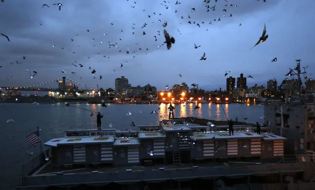 Pigeons wearing LED lights fly above their coops on board the Baylander, a decommissioned naval ship docked at the Brooklyn Navy Yard, Thursday, May 5, 2016, in New York. The 30-minute performance was part of artist Duke Riley's “Fly by Night” creation. (Photo by Kathy Willens/AP Photo)