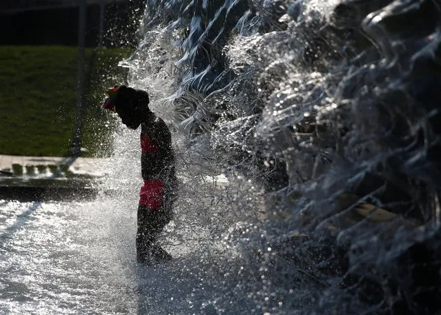 A girl cools off in a water feature in the Navy Yard neighborhood during a heat wave in Washington, U.S., July 20, 2019. (Photo by Eric Thayer/Reuters)