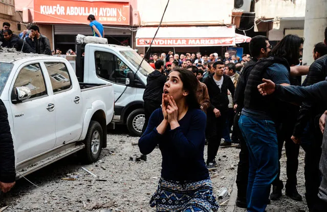 A woman reacts as she looks at the site of a strong blast near the riot police headquarters in the center of Diyarbakir, southeastern Turkey, on April 11, 2017. The explosion which shook police headquarters in Diyarbakir on Tuesday morning was an accident which occurred during repair work, the interior minister said. According to Turkey' s Interior Minister, no external forces had been involved in the incident in the restive majority Kurdish city which happened during repair work on armoured vehicles at police headquarters. He said one person was seriously hurt while another was trapped under rubble. (Photo by Ilyas Akengin/AFP Photo)