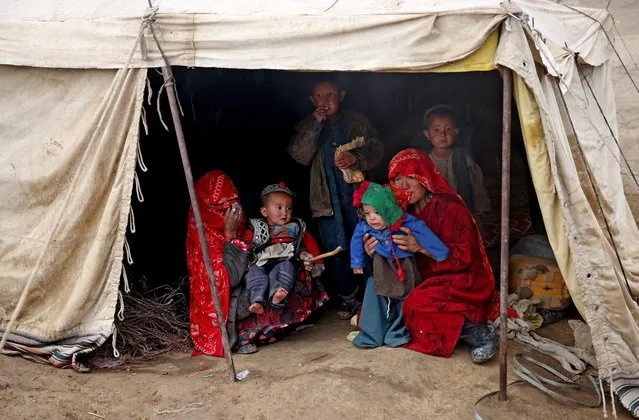 In this Sunday, May 4, 2014 photo, Survivors sit in a tent, near the site of Friday's landslide that buried Abi-Barik village in Badakhshan province, northeastern Afghanistan. Stranded and with no homes, many of the families have struggled to get aid. Some have gone to nearby villages to stay with relatives or friends, while others have slept in tents provided by aid groups. The unlucky ones have slept outside. (Photo by Massoud Hossaini/AP Photo)