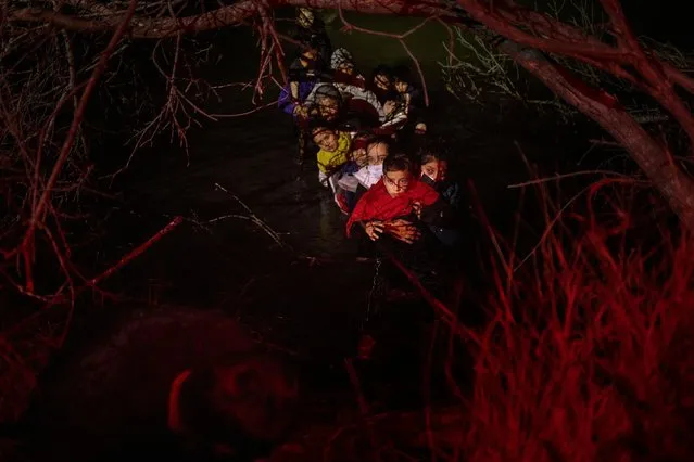 Linda Nallaely of Mexico holds her eight-year-old son Angel as they prepare to climb the bank of the Rio Grande river after wading with others into the United States from Mexico in Roma, Texas, U.S., April 8, 2022. (Photo by Adrees Latif/Reuters)