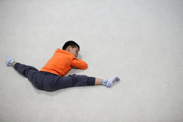 A boys lies on ground and stretches his legs during a break from gymnastics lessons at the Shanghai Yangpu Youth Amateur Athletic School in Shanghai, China, March 23, 2016. (Photo by Aly Song/Reuters)