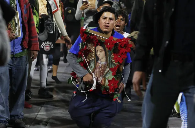 A pilgrim walks on his bare knees carrying an image of the Virgin of Guadalupe in an act of devotion, as he arrives at the Basilica of Guadalupe in Mexico City, Wednesday, December 11, 2019. Nationwide, devotees of the Virgin of Guadalupe make a pilgrimage to the Basilica in honor of her Dec. 12 feast day. (Photo by Marco Ugarte/AP Photo)
