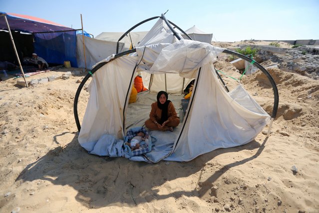 A displaced Palestinian woman and a child shelter in a cemetery, as Gaza health ministry announced that death toll has surpassed 40,000, amid the Israel-Hamas conflict, in Khan Younis, in the southern Gaza Strip on August 15, 2024. (Photo by Hatem Khaled/Reuters)