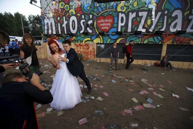 A newly married couple poses during a photo session near the main stage at the 21st Woodstock Festival in Kostrzyn-upon-Odra, Poland July 30, 2015. An estimated 200,000 people attended the ongoing festival, a brainchild of Polish journalist and social campaigner Jerzy Owsiak, on Friday. Owsiak initiated the event to say thank you to those who donated money to his GOCC charity organisation that delivers medical care for children. (Photo by Kacper Pempel/Reuters)