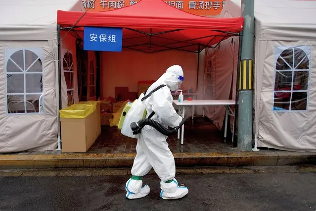 A worker wearing personal protective equipment (PPE) disinfects the entrance to a residential area on lockdown due to the recent Covid-19 coronavirus outbreaks in Beijing on May 10, 2022. Millions of people in Beijing stayed home on May 9 as China's capital tries to fend off a Covid-19 outbreak with creeping restrictions on movement. (Photo by Noel Celis/AFP Photo)