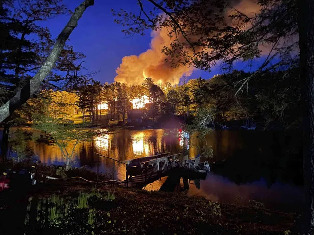 In this image provided by Maverick Irwin, Beach Cove Waterfront Inn is engulfed in flames as smoke from the fire rises into the night sky, Monday, May 23, 2022, in Boothbay Harbor, Maine. The state fire marshal's office is investigating the fire. The fire chief said no one was hurt. The owners were at the inn, which was scheduled to open on Memorial Day weekend. (Photo by Maverick Irwin via AP Photo)