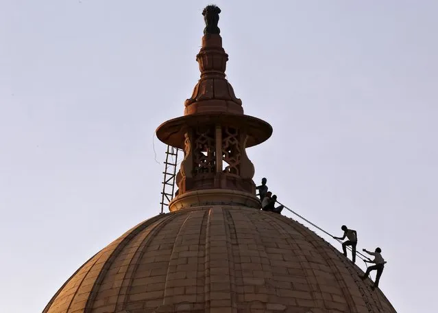 Labourers are silhouetted against the setting sun as they work on the dome of India's Ministry of Finance building in New Delhi, India, July 28, 2015. (Photo by Anindito Mukherjee/Reuters)