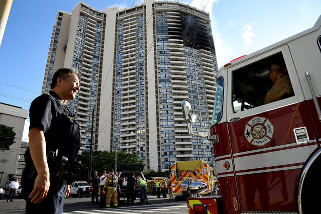 A police officer directs a fire truck at the Marco Polo apartment building after a fire broke out in it in Honolulu, Hawaii, July 14, 2017. (Photo by Hugh Gentry/Reuters)