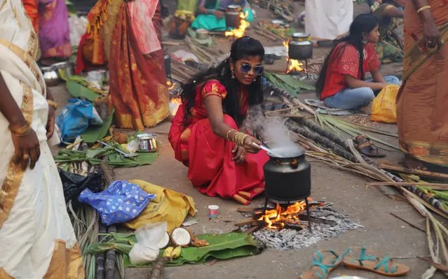 A devotee prepares a rice dish to offer to the Hindu sun god as they attend Pongal celebrations early morning along a roadside in Mumbai, India, January 15, 2020. (Photo by Francis Mascarenhas/Reuters)