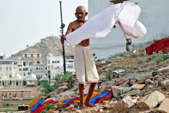 A man dries his clothes after taking a bath in a lake in Pushkar, in the desert state of Rajasthan, India June 23, 2016. (Photo by Himanshu Sharma/Reuters)