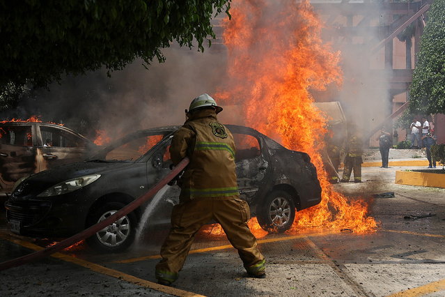 A firefighter extinguishes a burning car during a protest in Ayotzinapa, Mexico, 13 September 2024. Students from Ayotzinapa set fire to vehicles and vandalized the Guerrero state congress during a protest for the upcoming commemoration of the 10th anniversary of the disappearance of 43 classmates in the southern Mexican state of Guerrero. (Photo by José Luis de la Cruz/EPA)