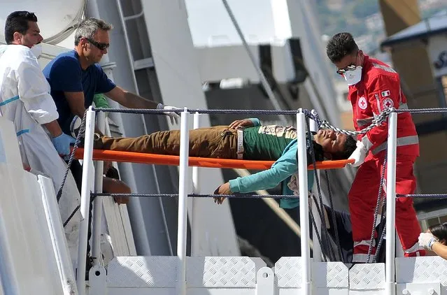 A migrant is helped to disembark from Italian Coast Guard vessel Diciotti in the Sicilian harbour of Palermo, Italy, August 20, 2015. (Photo by Guglielmo Mangiapane/Reuters)