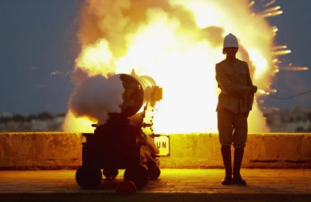 A National Heritage Trust historical reenactor in a Victorian-era Royal Malta Artillery uniform fires one of several cannons to mark the feast day of Saint John the Baptist, on the bastions of Valletta, in Malta, on June 23, 2014. (Photo by Darrin Zammit Lupi/Reuters)