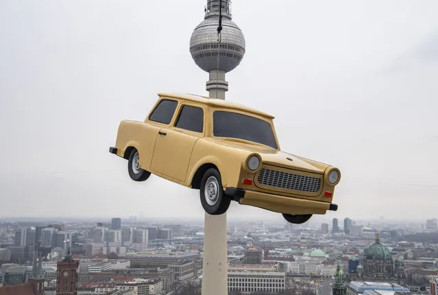 The likeness of a Trabant, east Germany's iconic car, is suspended over a Berlin skyline with its landmark the tv tower during a publicity stunt for an amusement park, on March 3, 2020. The “Little Big City” amusement park will be offering virtual 3D tours of the capital in a Trabant mock-up from March 2020. (Photo by John Macdougall/AFP Photo)