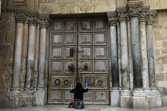 A woman prays in front of the Church of the Holy Sepulchre in the Old City of Jerusalem following the closure of the city for non-residents as a measure to contain the spread of the novel coronavirus, on March 30, 2020. (Photo by Menahem Kahana/AFP Photo)