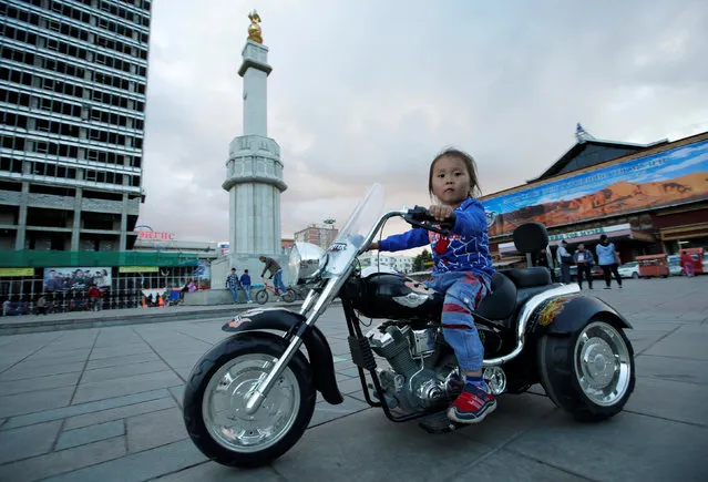 A girl rides an electric toy motorcycle at a square in Ulaanbaatar, Mongolia, June 29, 2016. Picture taken June 29, 2016. (Photo by Jason Lee/Reuters)