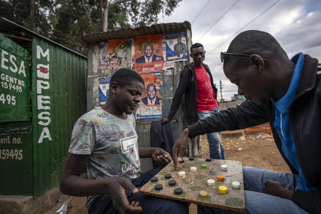 Men play a board-game on a street in the Kibera area of Nairobi, Kenya Friday, August 12, 2022. Vote-tallying in Kenya's close presidential election isn't moving fast enough, the electoral commission chair said Friday. (Photo by Ben Curtis/AP Photo)