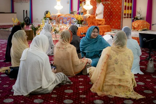 The faithful pray before the thakt, or throne, where the Guru Granth Sahib, the Sikh holy book, resides during prayer hours at the Guru Nanak Darbar of Long Island, a Sikh gurdwara, Wednesday, August 24, 2022, in Hicksville, N.Y. An Afghan Sikh family of 13 has found refuge in the diaspora community on Long Island where the Sikh community is helping family members obtain work permits, housing, healthcare and find schools for the children. (Photo by John Minchillo/AP Photo)