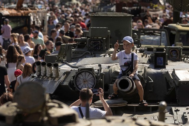 A boy sits atop of a tank at an exhibition of destroyed Russian military vehicles and weapons, dedicated to the upcoming country's Independence Day, amid Russia's attack on Ukraine, in the centre of Kyiv, Ukraine on August 21, 2022. (Photo by Valentyn Ogirenko/Reuters)