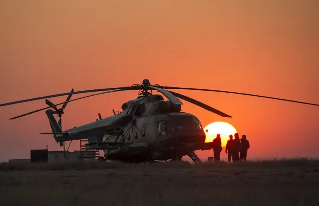 Ground support personnel are seen waiting to take off in their helicopter to support the Soyuz TMA-12M spacecraft, landing with International Space Station (ISS) crew members NASA astronaut Steve Swanson and Russian cosmonauts Alexander Skvortsov and Oleg Artemyev, at Dzhezkazgan September 11, 2014. (Photo by Bill Ingalls/Reuters/NASA)