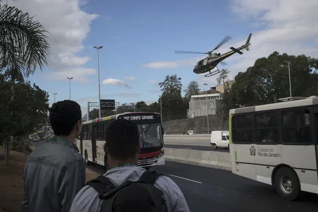 A Brazil's national security force helicopter flies over Avenida Brasil during a police operation in search for criminals at the Mare complex of slums during the 2016 Summer Olympics in Rio de Janeiro, Brazil, Thursday, August 11, 2016. A police officer is recovering from a life-saving surgery after he and two others sent to Rio de Janeiro for the Olympics were shot at after getting lost near a slum. (Photo by Felipe Dana/AP Photo)