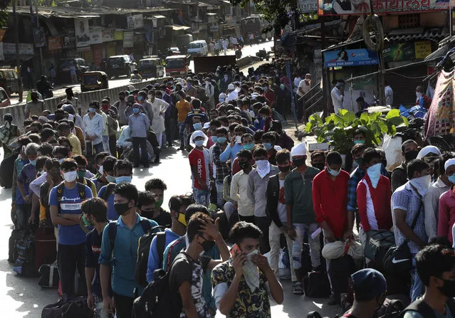 Migrant workers line up to board buses for their onward journey by train to their home states, at Dharavi, one of Asia's largest slums, in Mumbai, India, Friday, May 22, 2020. India's lockdown was imposed on March 25 and has been extended several times. On May 4, India eased lockdown rules and allowed migrant workers to travel back to their homes, a decision that has resulted in millions of people being on the move for the last two weeks. (Photo by Rafiq Maqbool/AP Photo)