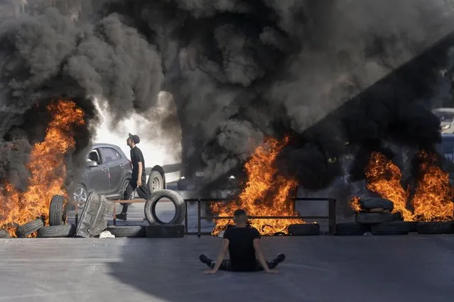 Tires set fire by Palestinians burn at the site where two Palestinians were shot and killed by the Israeli army in the Jalazone refugee camp near the city of Ramallah, West Bank, Monday, October 3, 2022. Palestinian officials say the Israeli military has killed two Palestinians in the occupied West Bank. The Israeli military says it was on an arrest raid early Monday and alleges the two suspects tried to ram their car into soldiers, a claim that could not be independently verified. (Photo by Majdi Mohammed/AP Photo)