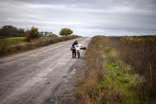 An elderly woman pushes her bicycle leaving the town of Bakhmut, in eastern Ukraine's Donbas region, on October 23, 2022, amid the Russian invasion of Ukraine. (Photo by Dimitar Dilkoff/AFP Photo)