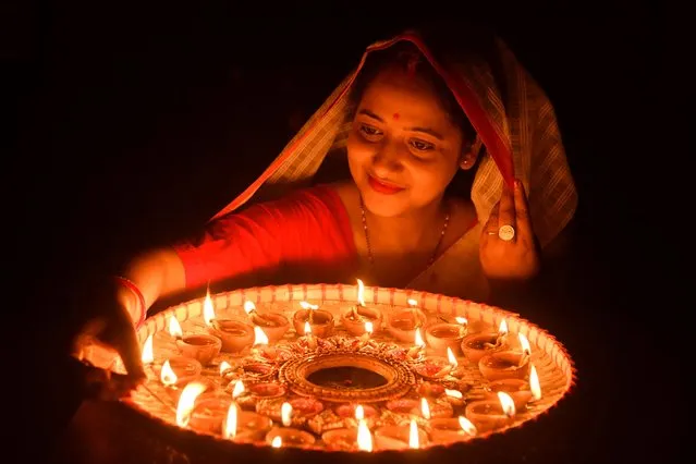 A woman lights earthen lamps on the occasion of Diwali, the Hindu festival of lights, at her house in Guwahati on October 24, 2022. (Photo by Biju Boro/AFP Photo)
