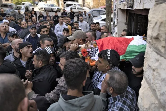 Palestinian mourners carry the body of Daoud Mahmoud Khalil Rayan, 42, during his funeral in the West Bank village of Beit Duqqu, southwest of Ramallah, Thursday, November 3, 2022. The Palestinian Health Ministry said that Rayan was killed by Israeli fire in the occupied West Bank. Israeli police said it happened during a raid in the territory and alleged the man threw a firebomb at the forces. (Photo by Nasser Nasser/AP Photo)