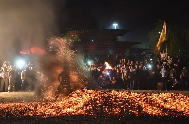 People take part in a performance next to a fire during a traditional ritual in Jinhua, Zhejiang province, September 18, 2015. Locals pray for good fortune and pay respects to their ancestors during the ritual, called “Lianhuo”. The ritual performance involved some 27 men who walked on ashes and fueled the fire, local media reported. (Photo by Reuters/Stringer)