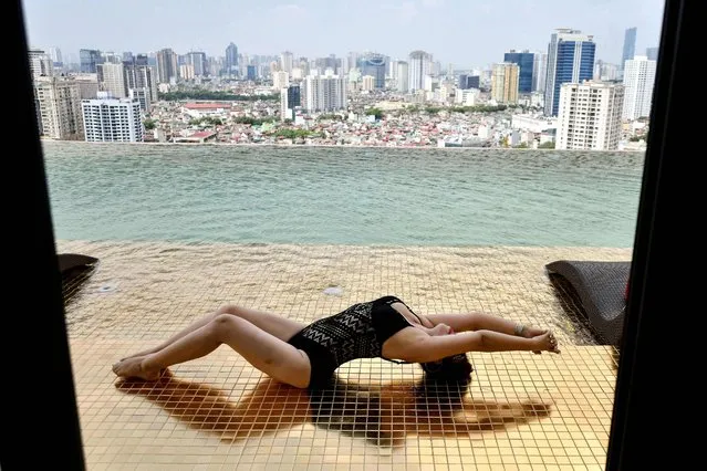 A guest poses for photographs at the infinity pool of the newly-inaugurated Dolce Hanoi Golden Lake hotel, the world's first gold-plated hotel, in Hanoi on July 2, 2020. (Photo by Manan Vatsyayana/AFP Photo)