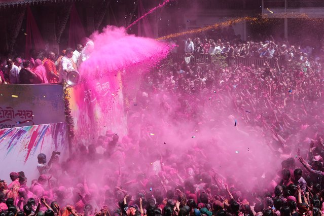 Devotees cheer as colored powder and water is sprayed on them during celebrations of Holi, the Hindu festival of colors, at the Kalupur Swaminarayan temple in Ahmedabad, India, Friday, March 14, 2025. (Photo by Ajit Solanki/AP Photo)