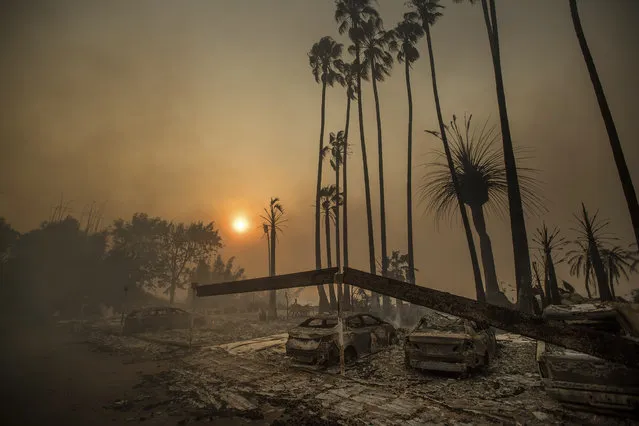 Smoke rises behind a leveled apartment complex as a wildfire burns in Ventura, Calif., on Tuesday, December 5, 2017. Over 100 structures have burned so far in Ventura County, officials said. (Photo by Noah Berger/AP Photo)