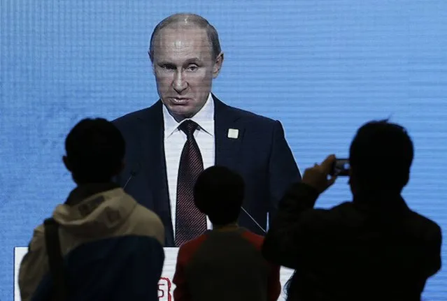 Journalists (front) watch a live broadcast on an electronic screen showing Russia's President Vladimir Putin giving a speech during the APEC CEO Summit, at the China National Convention Centre (CNCC), in Beijing, November 10, 2014. (Photo by Jason Lee/Reuters)