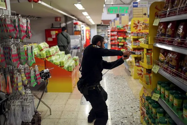 An Israeli policeman searches a supermarket inside the Central Jerusalem Bus Station after police said a woman was stabbed by a Palestinian outside the bus station October 14, 2015. (Photo by Noam Moskowitz/Reuters)